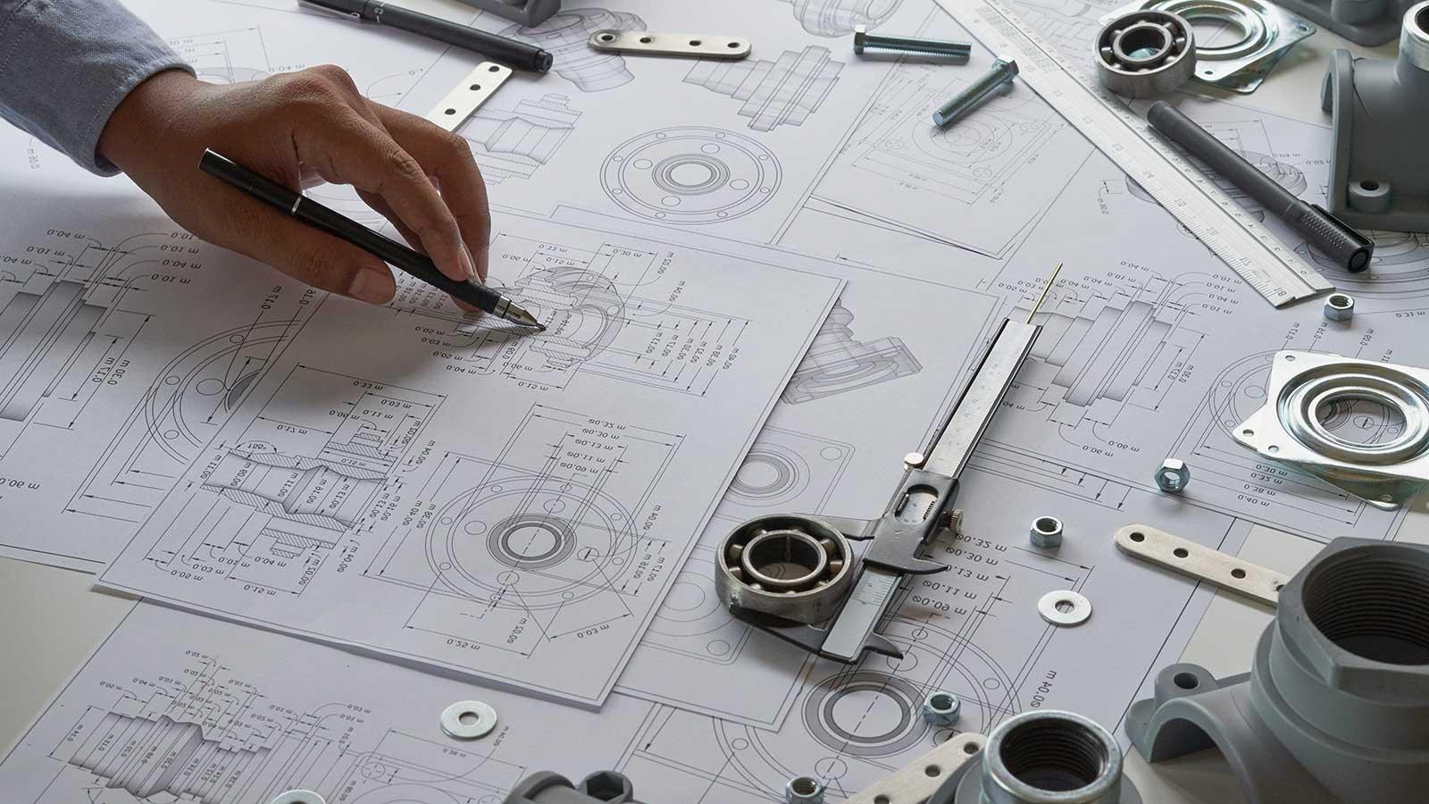 esball国际平台客户端的机械工程师正在看代表机械工程项目的蓝图 